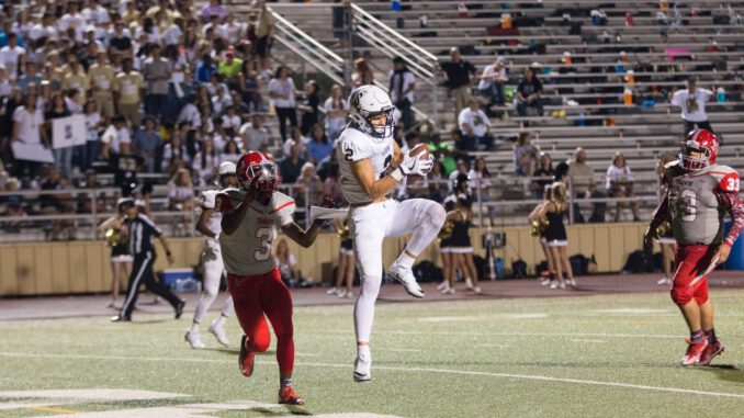 man catching brown football on stadium