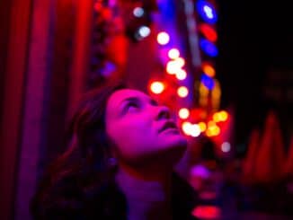 woman in black shirt with string lights on her face