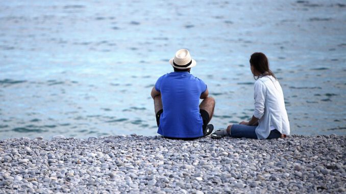 Mann und Frau sitzen am Strand, über dts Nachrichtenagentur