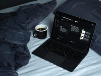 black laptop computer on white bed