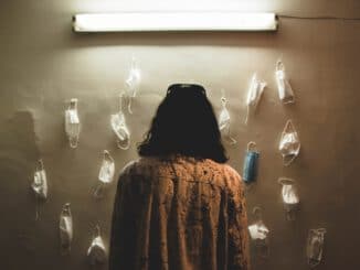 woman in brown and black coat standing in front of white wall
