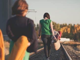 group of people walking on train tracks during sunrise